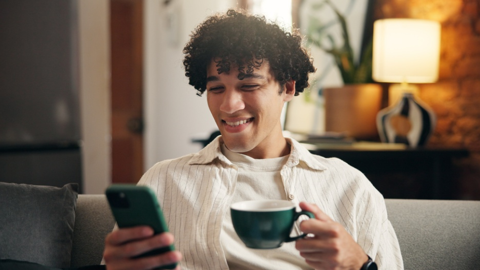 young man holidng coffee cup and cell phone